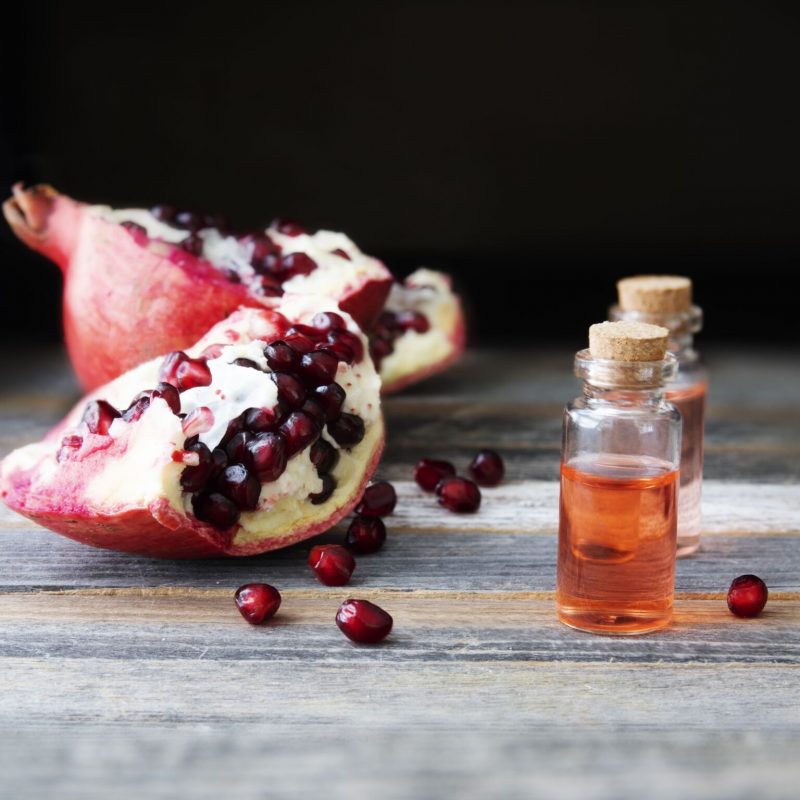 Fresh pomegranate pieces and a small bottle of pomegranate extract.